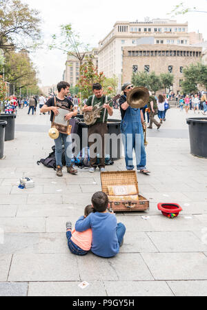 Zwei Kinder sitzen und hören auf die 'Los Boozan Dukes' Band spielen auf der Straße in Barcelona in der Nähe der gotischen Q Stockfoto