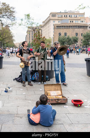 Zwei Kinder sitzen und hören auf die 'Los Boozan Dukes' Band spielen auf der Straße in Barcelona in der Nähe der gotischen Q Stockfoto