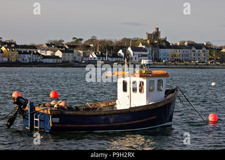 Eine kleine Hummer Fischerboot im Hafen Donaghadee, Nordirland, mit der Stadt und Schiesspulver Storage Magazine hinter sich. Stockfoto