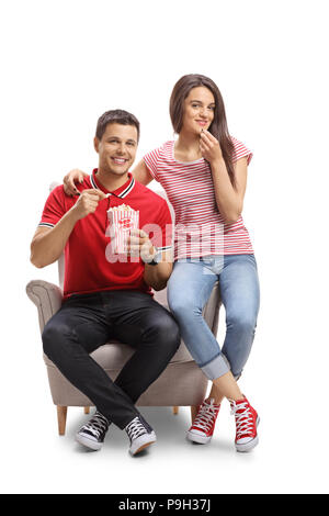 Junges Paar in einen Sessel mit Popcorn auf weißem Hintergrund sitzen Stockfoto