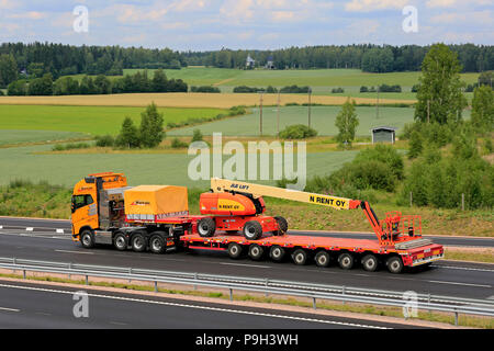 Gelbe Volvo FH Auflieger von Rantala Transporte JLG 860 SJ Teleskoparm heben am Anhänger an der Autobahn im Sommer. Salo, Finnland - 13. Juli 2018. Stockfoto