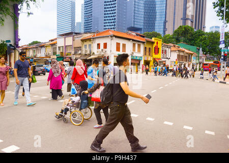 Singapur - 17. Februar 2017: Menschen beim Überqueren der Straße in Chinatown von Singapur. Moderne Wolkenkratzer von Downtown Singapur auf einem Hintergrund. Stockfoto