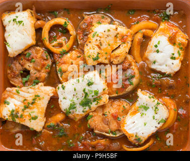 Ein Fisch Eintopf aus Zwiebeln, Knoblauch, Tomaten, gemischte Kräuter und Fisch mit meeraal Steaks, Tintenfischringe und Pollack Filets mit Petersilie garniert. Fi Stockfoto