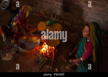 Eine Frau Chapatti kocht auf offenem Feuer, in ihrer Küche im ländlichen Indien. Stockfoto