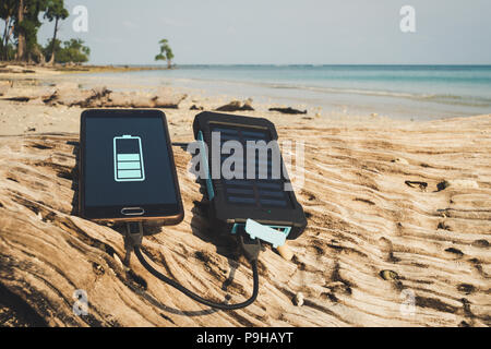 Alternative Energiequelle. Akku wird mit Solarenergie aufgeladen. Aufladen mobiler Geräte in das wilde. Island Beach. Powerbank Gebühren das Telefon auf den b Stockfoto