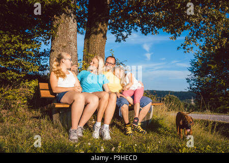 Familie ruht auf der Bank bei einem langen Spaziergang im Sommer Stockfoto