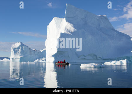 Zodiacs füllen mit Touristen Schwimmer unter enormen Eisberge in Scoresby-sund, Grönland Stockfoto