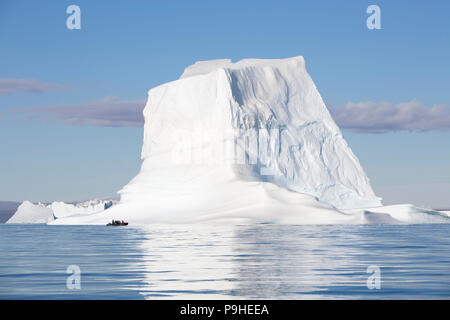 Zodiacs füllen mit Touristen Schwimmer unter enormen Eisberge in Scoresby-sund, Grönland Stockfoto