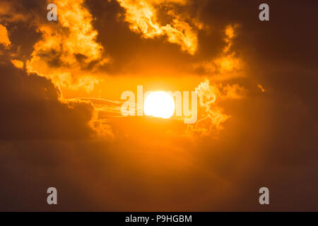 Blur roten blutigen Sonnenuntergang. Die Sonne guckt hinter den Wolken. Leuchtend gelben Himmel. die Sonne von Wolken umgeben. Abend licht Stockfoto