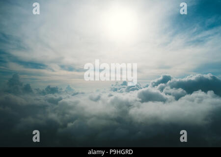 Ein Blick von hoch über den Wolken. Blick auf die Wolken aus dem Fenster des Flugzeugs. Nicht-Flugwetter. Die Sonne strahlt durch das dunkle Blau und gr Stockfoto