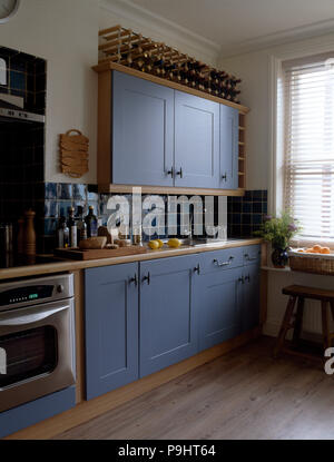 Wine Rack auf blau lackierte Schränke in einem modernen blau-weißen Küche mit Holzböden ausgestattet Stockfoto