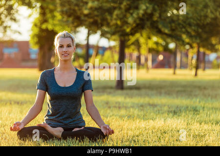 Blonde Frau Yoga im Park Stockfoto