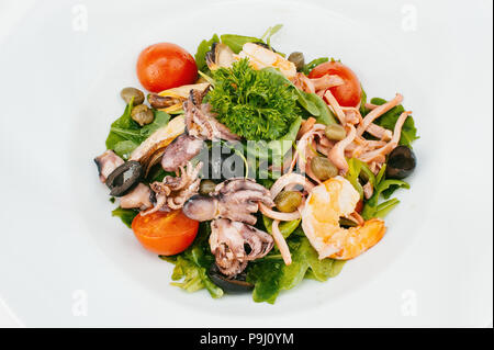 Frischer gemischter Salat mit Garnelen, Tintenfisch, Oliven und eingelegten Kapern isoliert auf weißem bachground Stockfoto