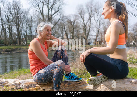 Ältere und junge Frau ruht auf log nach dem Sport Stockfoto