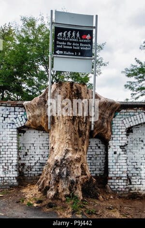 Berlin, Friedrichshain, RAW-Gelände. Werbung für Möbel shop auf geschnitzt alten Baumstamm Neben verwitterten Mauer Stockfoto