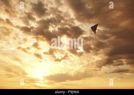Drachen fliegen in den Himmel mit Wolken bei Sonnenuntergang Stockfoto