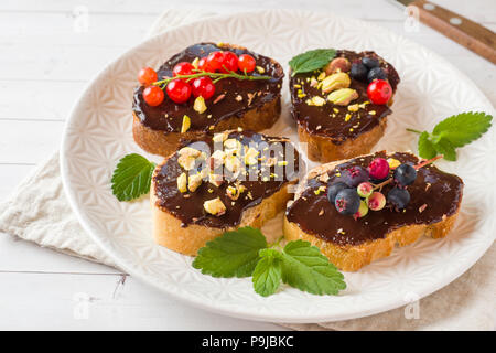 Sandwiches mit Schokoladencreme, Pistazien und frische Beeren auf einer Platte Stockfoto