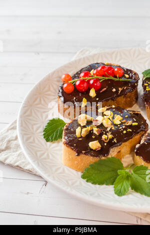 Sandwiches mit Schokoladencreme, Pistazien und frische Beeren auf einer Platte Stockfoto