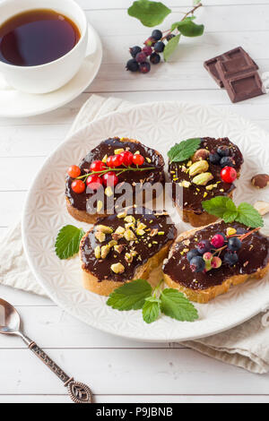 Sandwiches mit Schokoladencreme, Pistazien und frische Beeren auf einer Platte Stockfoto