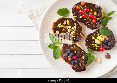 Sandwiches mit Schokoladencreme, Pistazien und frische Beeren auf einer Platte Stockfoto