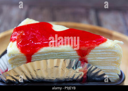 Stück crape Kuchen mit Erdbeersauce auf Holzplatte Hintergrund Stockfoto