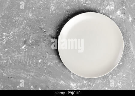 Blick von oben auf die Matte runde leeren Teller auf dunklem Hintergrund. Stockfoto