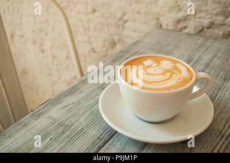 Eine Tasse frischen Cappuccino mit schönen latte Kunst auf weißen und grauen Holztisch. Stockfoto