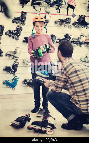 Männliche Shop Assistant hilft jungen auf Walze zu versuchen - Skates, Sportgeschäft Stockfoto