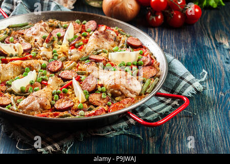 Traditionelle Paella mit Huhn Beine, Chorizo Wurst und Gemüse in paellera serviert. Spanische Küche Stockfoto