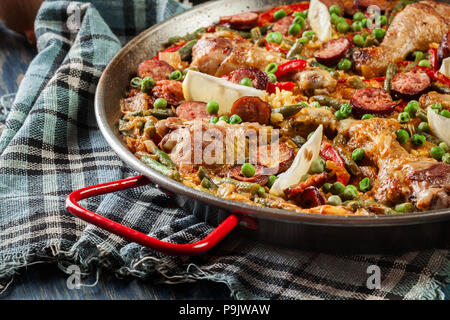 Traditionelle Paella mit Huhn Beine, Chorizo Wurst und Gemüse in paellera serviert. Spanische Küche Stockfoto