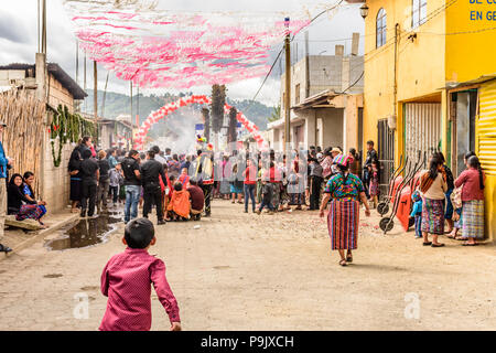 Parramos, Guatemala - Dezember 29, 2016: Einheimische einschließlich der indigenen Maya Frauen in traditioneller Kleidung & Volkstänzer in Tracht Prozession folgen. Stockfoto