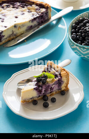 Tea Time. Hausgemachten blueberry Cheesecake mit Ricotta auf blauem Papier Hintergrund Stockfoto