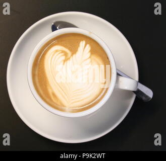 Kaffee in eine weiße Tasse mit Untertasse Tasse auf Weißen und silbernen Löffel auf der Untertasse. Qualifizierte Barista hat die Oberfläche der Schaum eingerichtet. Foto Russell Moore. Stockfoto