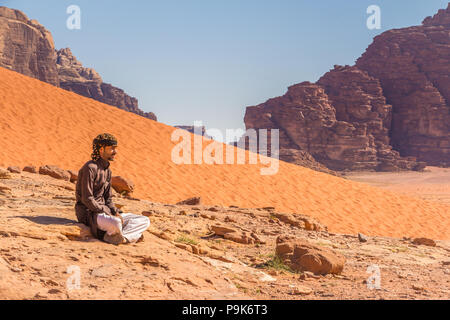 Wadi Rum, Jordanien - 30. April 2016: Beduinemann ruht auf einem Felsen in der Wüste Wadi Rum in Jordanien Stockfoto