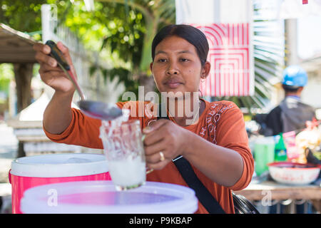 SUMBAWA BESAR, Indonesien - 29. AUGUST 2017: Unbekannter schönen Frau, die Vorbereitung und den Verkauf von Kokosnuss Wasser. Stockfoto