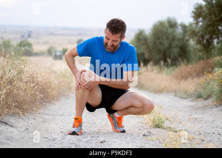 Junge Sportart Mann mit starken athletische Beine Knie mit den Händen in den Schmerz nach Leiden Muskelverletzungen während eines laufenden Training Training in aspha Stockfoto