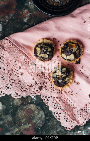 Törtchen mit Schokolade gefüllt mit Mandeln bestreut. Stockfoto