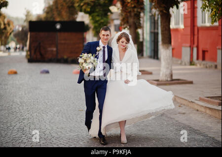 Atemberaubende Hochzeit paar Wandern und Spaß auf der alten Straße im Herbst. Stockfoto