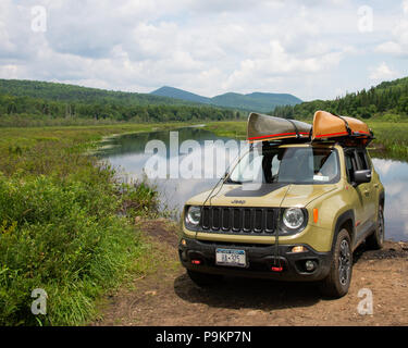 Ein grüner Jeep Renegade trailhawk an der Kunjamuk Fluss in den Adirondack Mountains geparkt mit zwei leichten Hornbeck kevlar Kanus auf dem Dach. Stockfoto