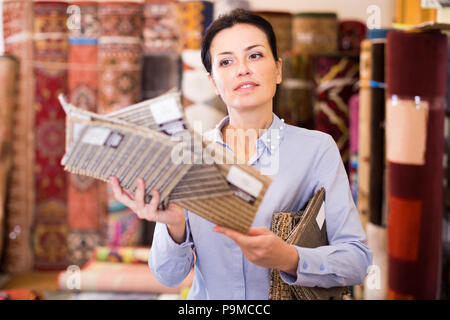 Lächelnd weibliche demonstrieren, Varianten der Teppiche home Einrichtungshaus Stockfoto