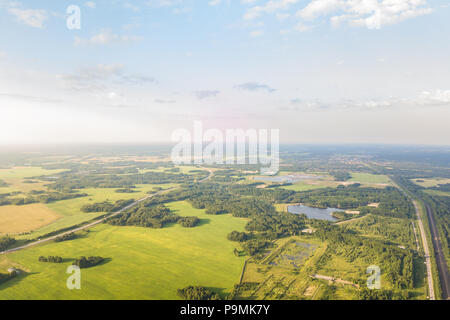 Hubschrauber Drohne erschossen. Luftaufnahmen von grünen Wald mit See- und Straßenverkehr, grünen Gras. Stockfoto