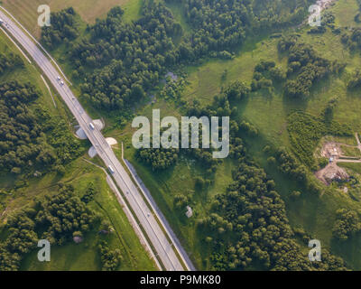 Hubschrauber Drohne erschossen. Luftaufnahmen von grünen Wald mit Straße, grünes Gras. Stockfoto