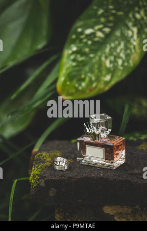 Flasche luxus Parfum- und Trauringe. Natur tropischen Hintergrund Stockfoto