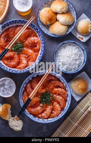 Pikante asiatische Garnelen in Tomatensauce mit Reis, Brötchen und Bier, Ansicht von oben Stockfoto