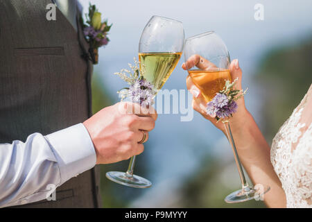 Mann und Frau Hände halten zwei Sektgläser mit Blumen für die Hochzeit Zeremonie dekoriert Stockfoto