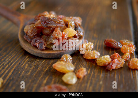 Süße getrocknete Rosinen in Löffel aus Holz auf Holz- Hintergrund Stockfoto