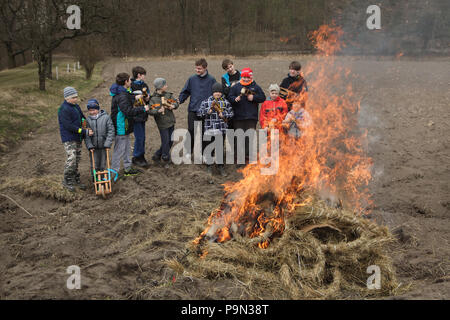 Schöne traditionelle Ostern Prozession bekannt als Vodění Jidáše (Judas) im Dorf Stradouň in Pardubice, Tschechische Republik. Kinder brennen das Stroh Anzug von Judas auf den Bereich außerhalb des Dorfes nach der Prozession am 31. März 2018. Am frühen Morgen des Karsamstag, der älteste Teenager in das Dorf liegt in einem lächerlichen Stroh Anzug gekleidet. Er soll Judas Iskariot auf diese Weise durchzuführen. Das Tragen dieser obskuren Outfit, hat er März durch das Dorf von Haus zu Haus von anderen Jungen, die Twist hölzernen Ratschen und ein Lied über Judas, der seinen Master t verraten Singen begleitet Stockfoto