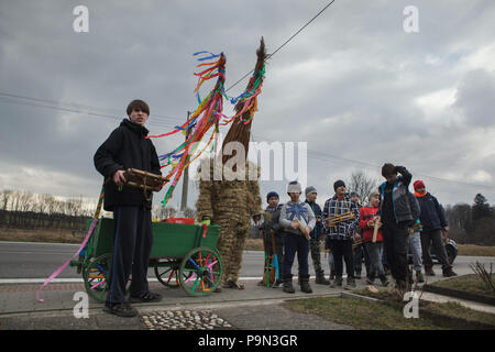 Schöne traditionelle Ostern Prozession bekannt als Vodění Jidáše (Judas) im Dorf Stradouň in Pardubice, Tschechische Republik. Eine Person in einem Stroh Anzug, die Judas hält vor einem Haus mit jungen Verdrehen hölzernen Ratschen und mit einem Teenager, der eine Karre für Spenden bei der Prozession am 31. März 2018 begleitet gekleidet. Am frühen Morgen des Karsamstag, der älteste Teenager in das Dorf liegt in einem lächerlichen Stroh Anzug gekleidet. Er soll Judas Iskariot auf diese Weise durchzuführen. Das Tragen dieser obskuren Outfit, hat er März durch das Dorf von Haus zu ho Stockfoto