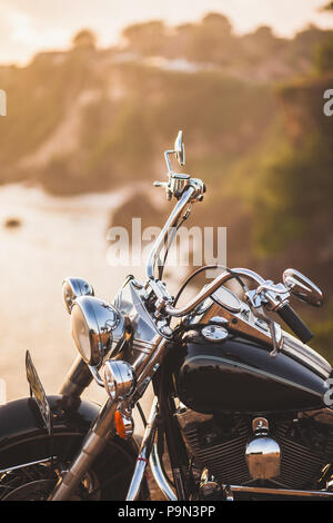 Alte Oldtimer Motorrad stehen am Rand der Klippe in warmes Sonnenlicht bei Sonnenaufgang, glänzend Details zu Fahrrad close-up Stockfoto