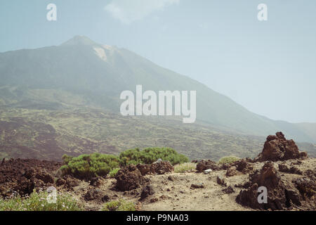 Vulkan Teide auf Teneriffa durch den Dunst und Sand von La Calima mit trockenen Buschland und Lava Felsformationen in der Landschaft versteckt Stockfoto